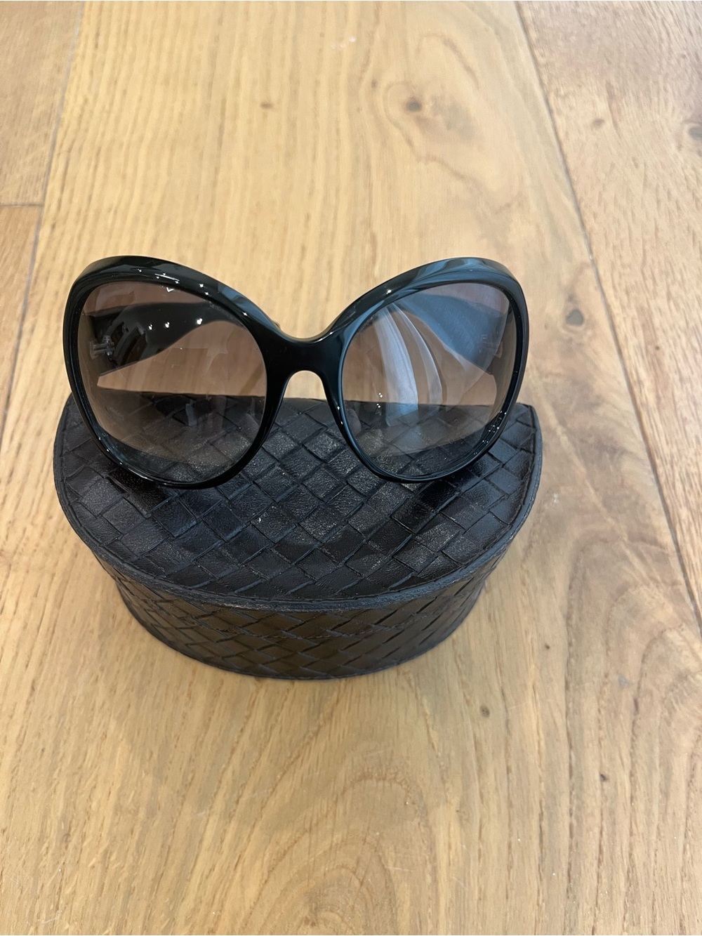 Bottega Veneta black plastic sunglasses with intrecciato leather at temples.